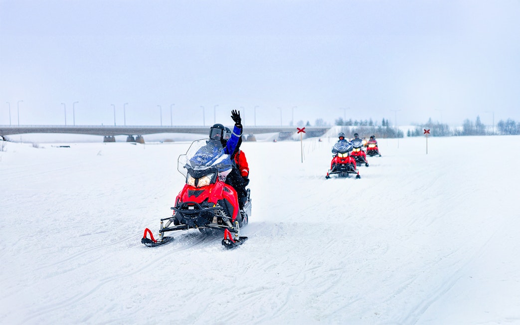 Snowmobilers on frozen lake in winter, Lapland.