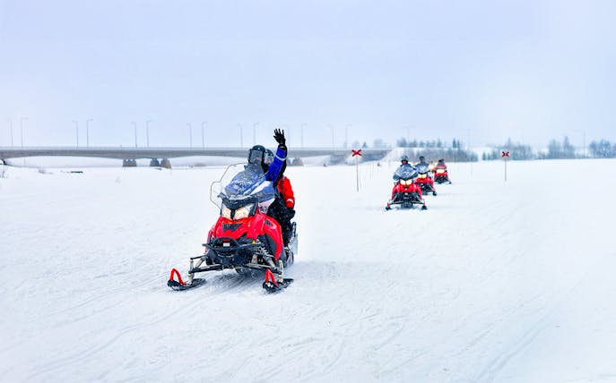 Snowmobilers on frozen lake in winter, Lapland.