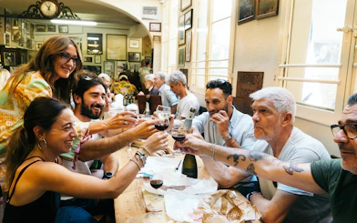 Group enjoying wine and food at a local restaurant during a guided food tour in Bologna.
