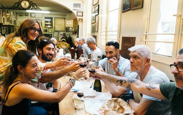Group enjoying wine and food at a local restaurant during a guided food tour in Bologna.