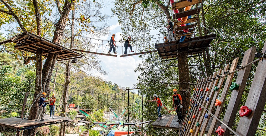 People crossing hanging bridges in a forest adventure park.