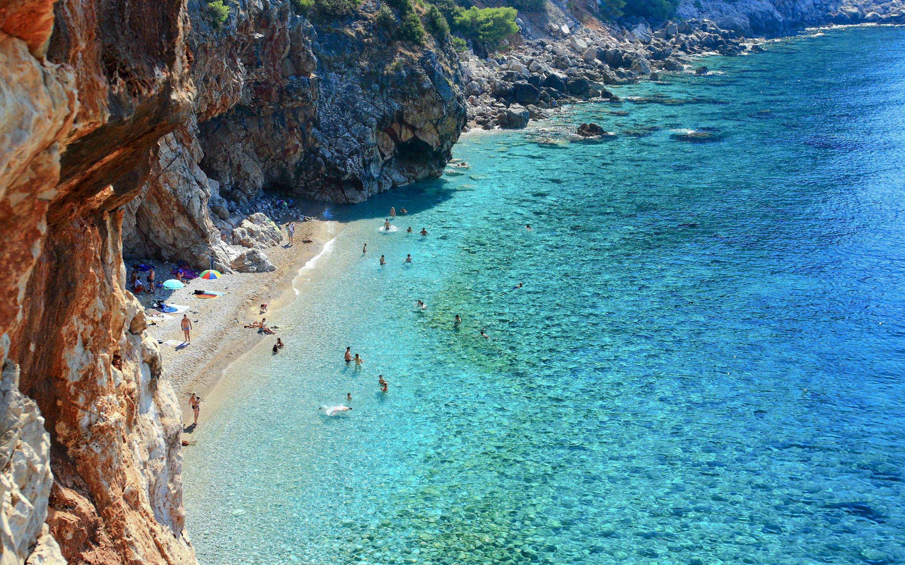 Pasjaca Beach with swimmers and rocky cliffs near Dubrovnik, Croatia.