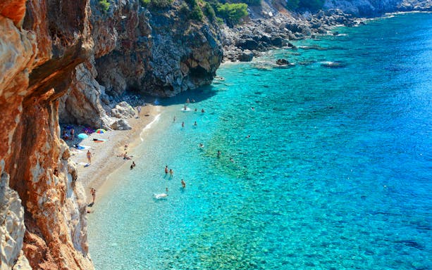 Pasjaca Beach with swimmers and rocky cliffs near Dubrovnik, Croatia.