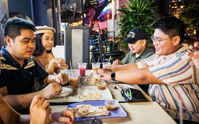 Group enjoying roti prata and drinks at a Singapore street food night market.