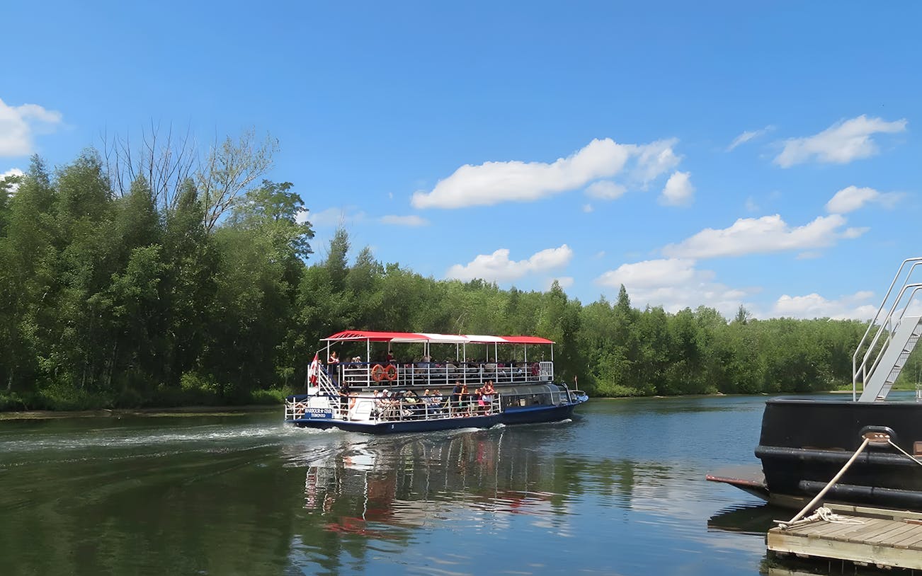Cruise boat on Toronto Harbour with passengers enjoying the view of lush green islands.