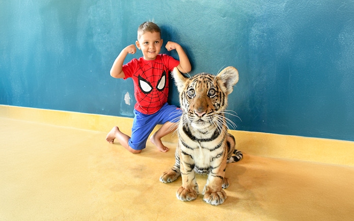 Child posing with tiger cub at Tiger Park Pattaya.