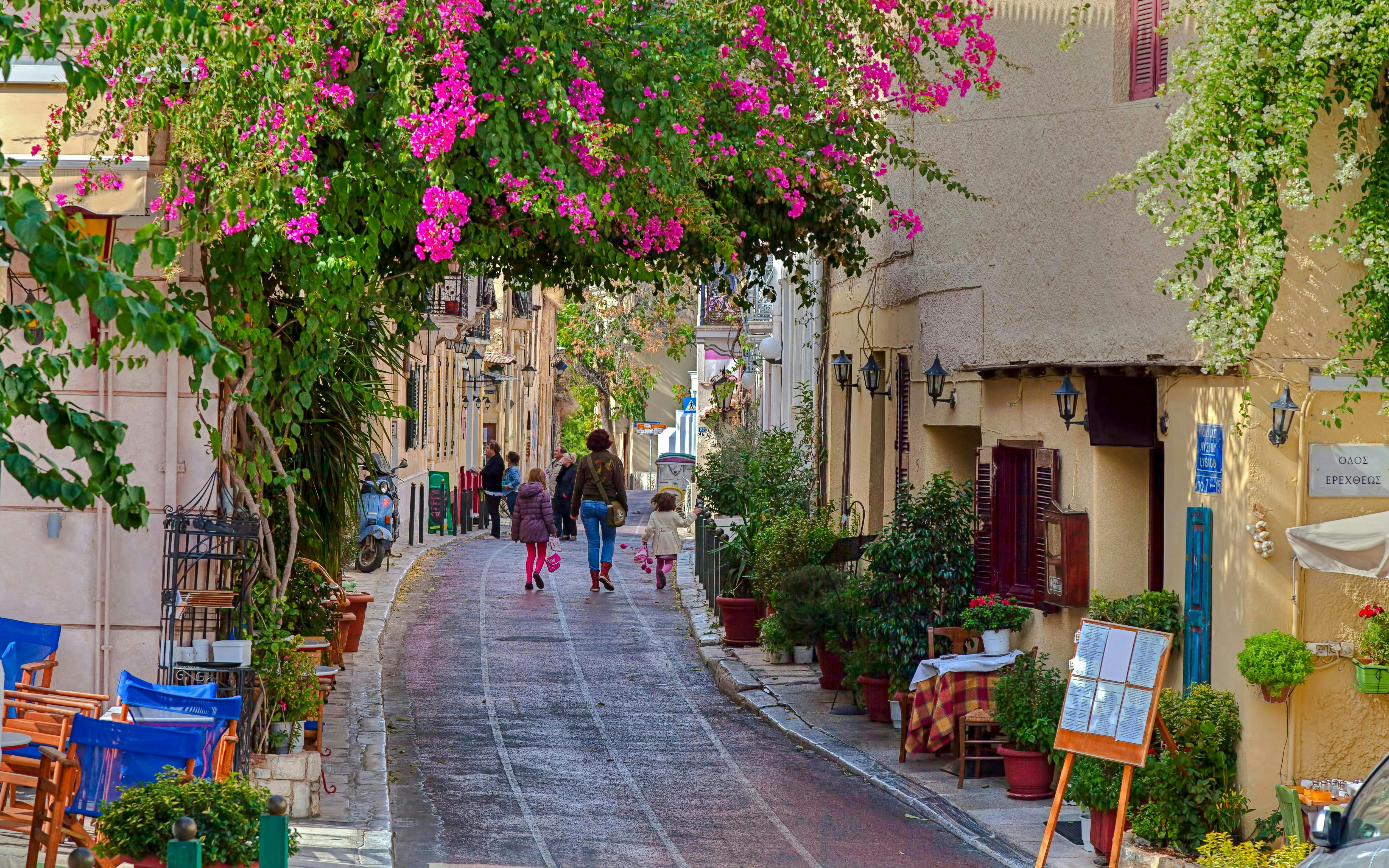 Street with traditional houses and vibrant flowers in Plaka, Athens.