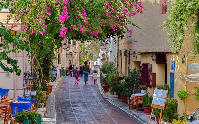 Street with traditional houses and vibrant flowers in Plaka, Athens.