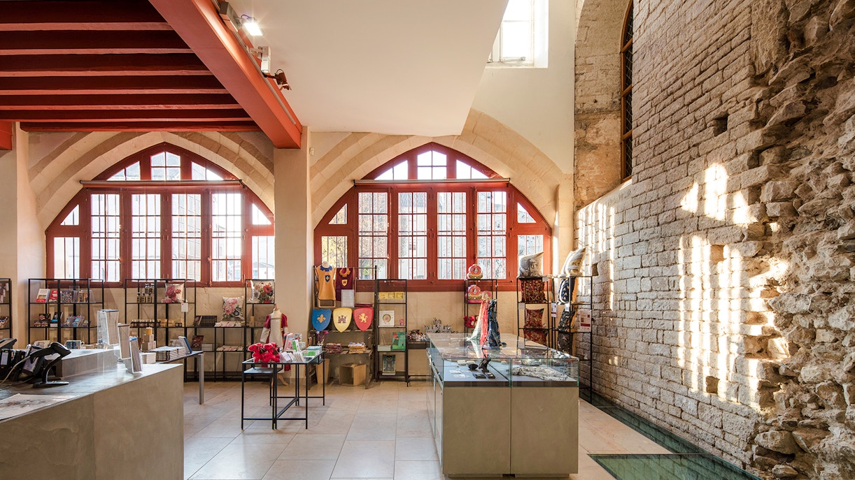 Gift shop interior at Abbaye de Cluny, Lyon, France, featuring medieval-themed merchandise.