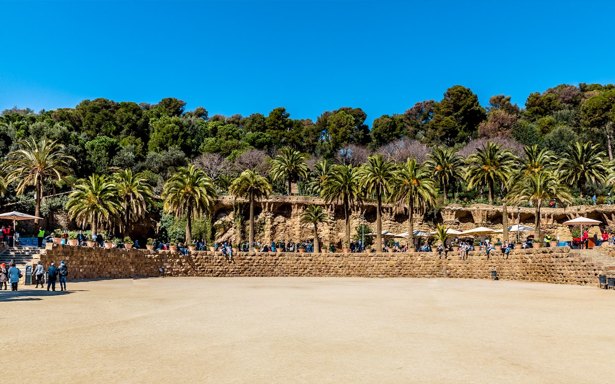 Parc Guell Nature Square with stone terrace and palm trees in Barcelona.