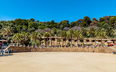 Parc Guell Nature Square with stone terrace and palm trees in Barcelona.