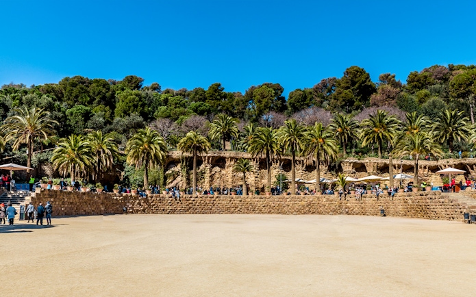 Parc Guell Nature Square with stone terrace and palm trees in Barcelona.