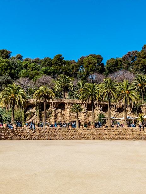 Parc Guell Nature Square with stone terrace and palm trees in Barcelona.