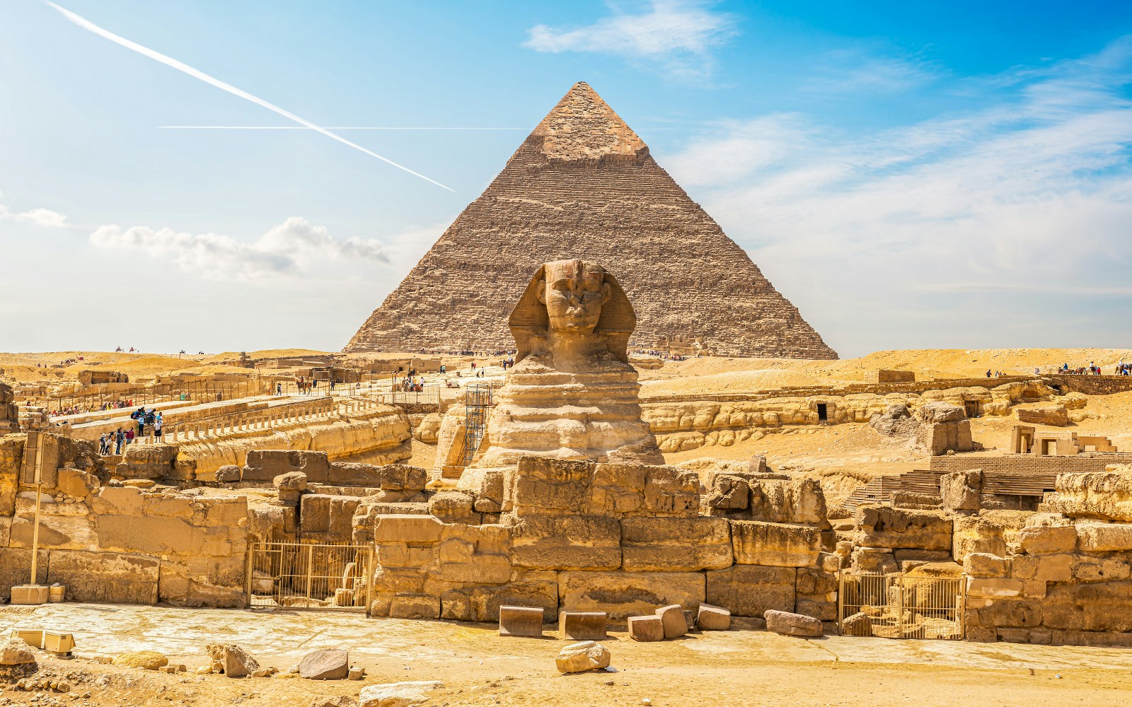 Sphinx and Pyramid of Khafre in Giza, Cairo, with tourists exploring the site.