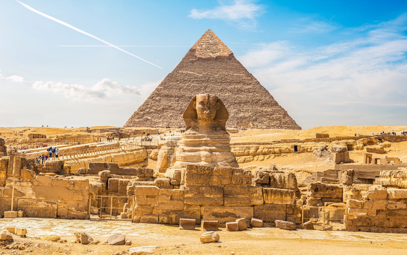 Sphinx and Pyramid of Khafre in Giza, Cairo, with tourists exploring the site.