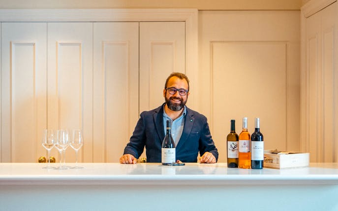 Man presenting wine bottles at The Wine School workshop.