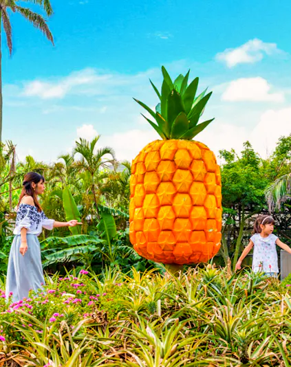 Visitors exploring giant pineapple sculpture at Nago Pineapple Park, Okinawa.