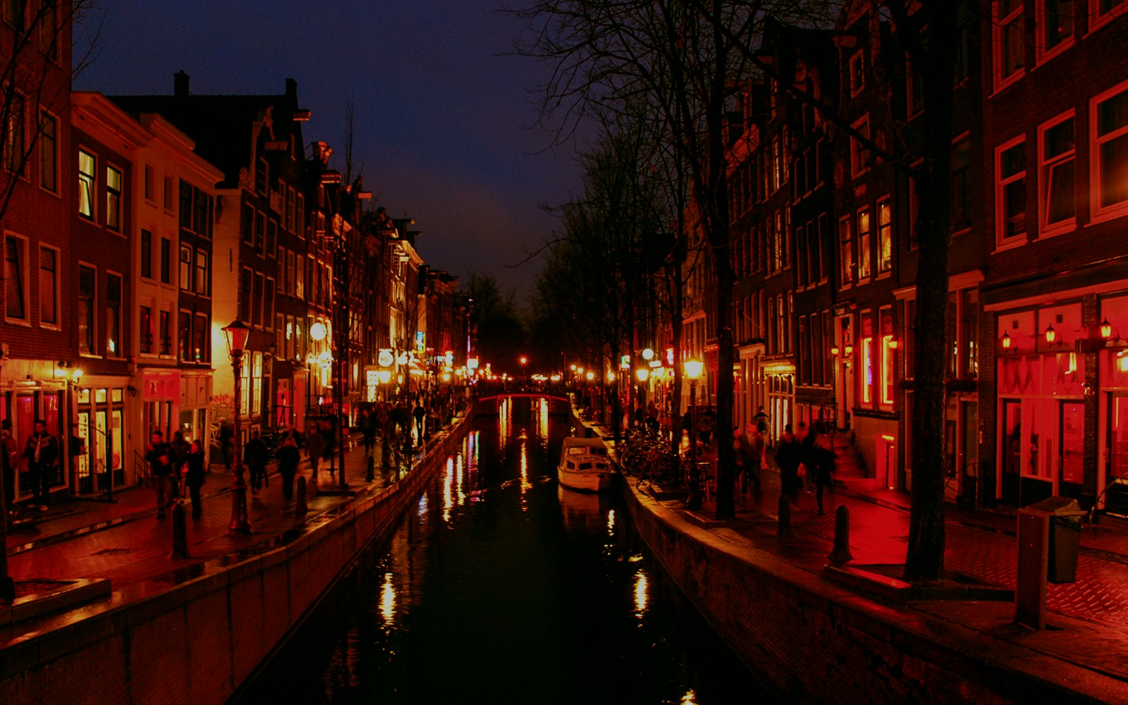 Menschen laufen rechts und links eines Kanals bei Nacht im Amsterdamer Rotlichtviertel