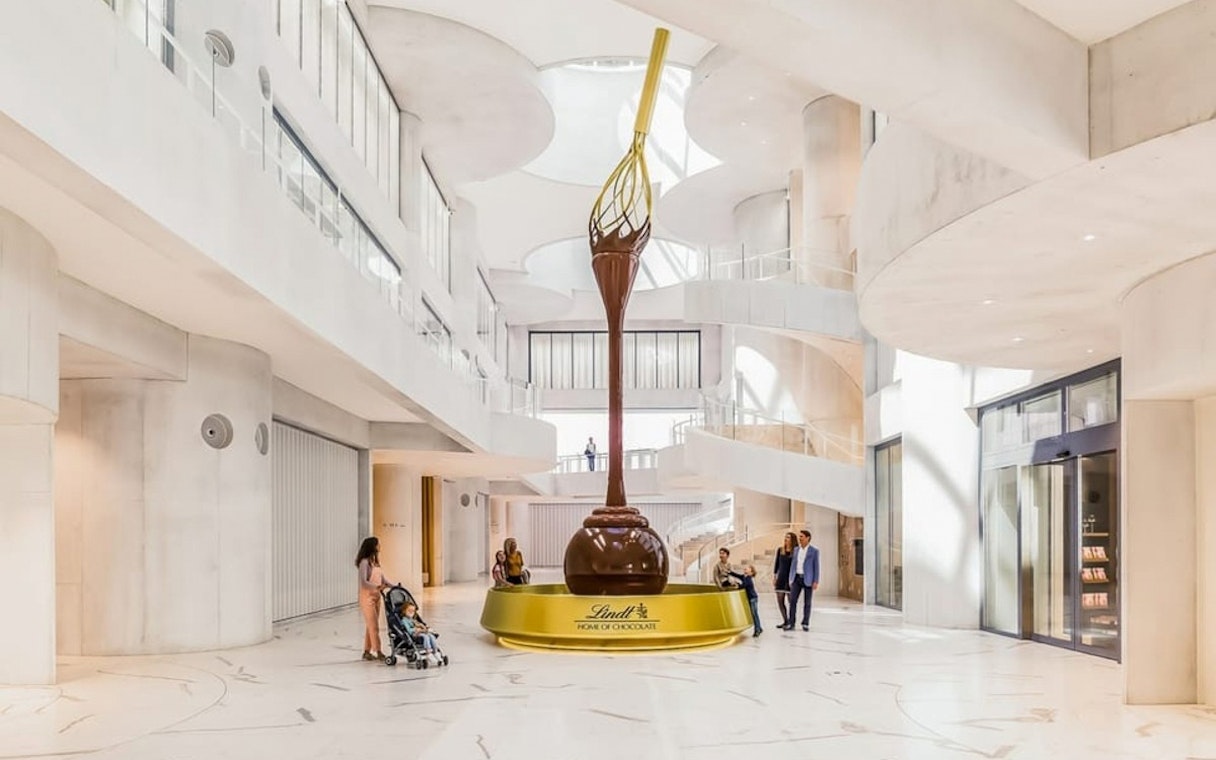 Lindt Home of Chocolate Museum interior with large chocolate fountain and visitors.