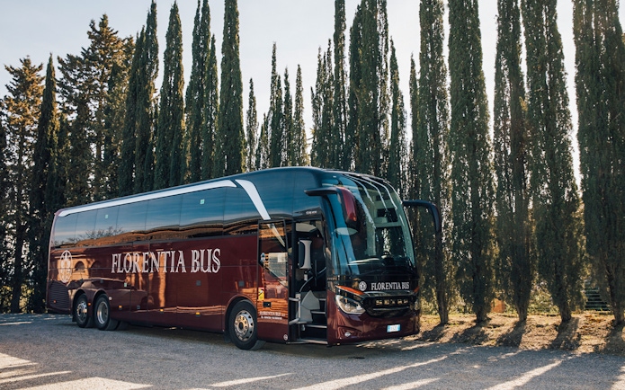 Tour bus parked among cypress trees in Tuscany, Italy.