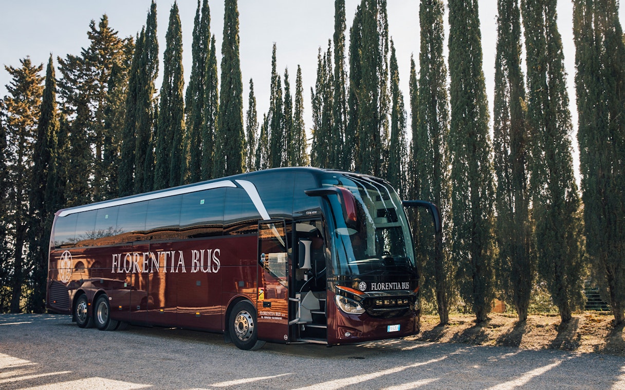 Tour bus parked among cypress trees in Tuscany, Italy.