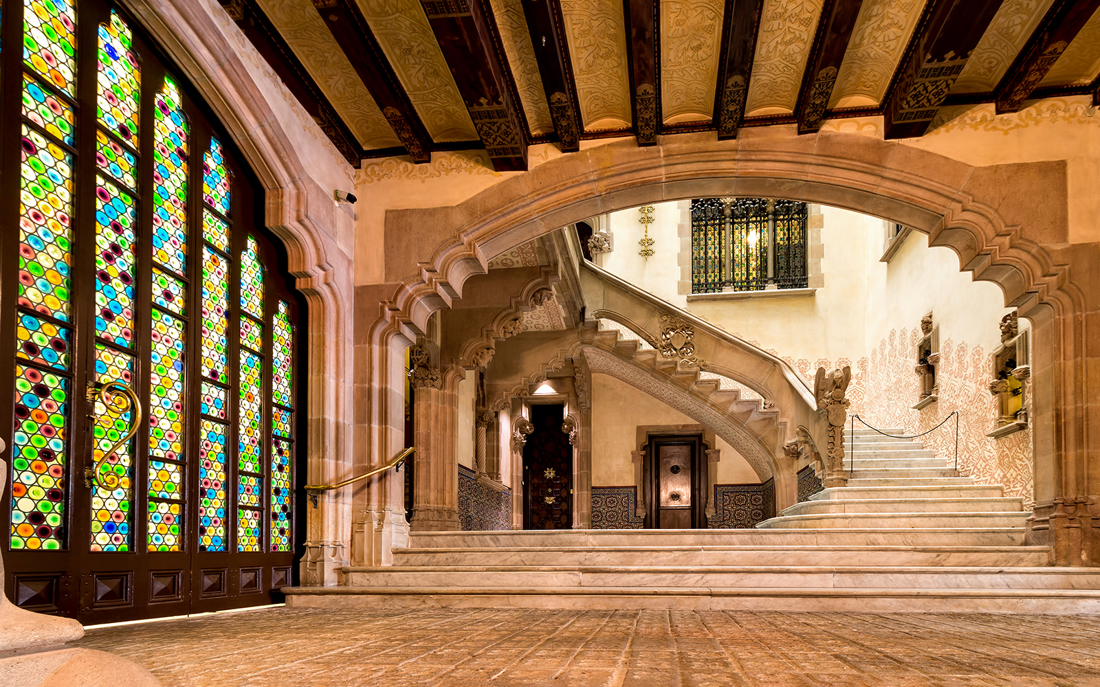 Interior of Casa Amatller in Barcelona with stained glass windows and ornate staircase.