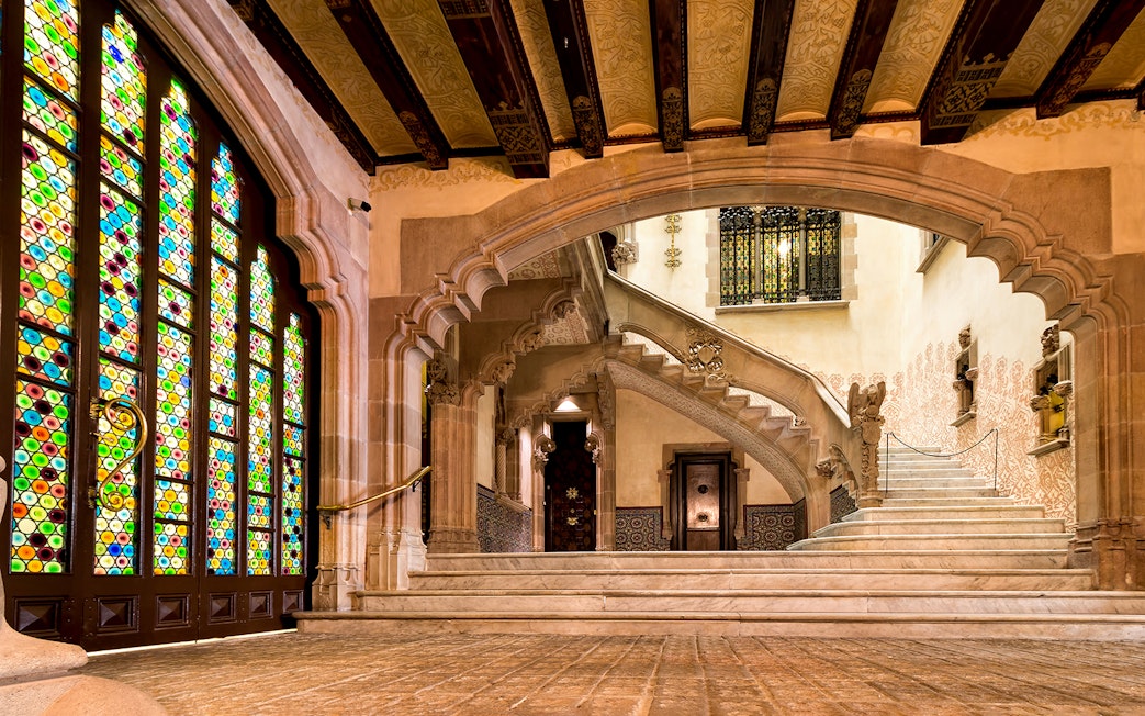 Interior of Casa Amatller in Barcelona with stained glass windows and ornate staircase.