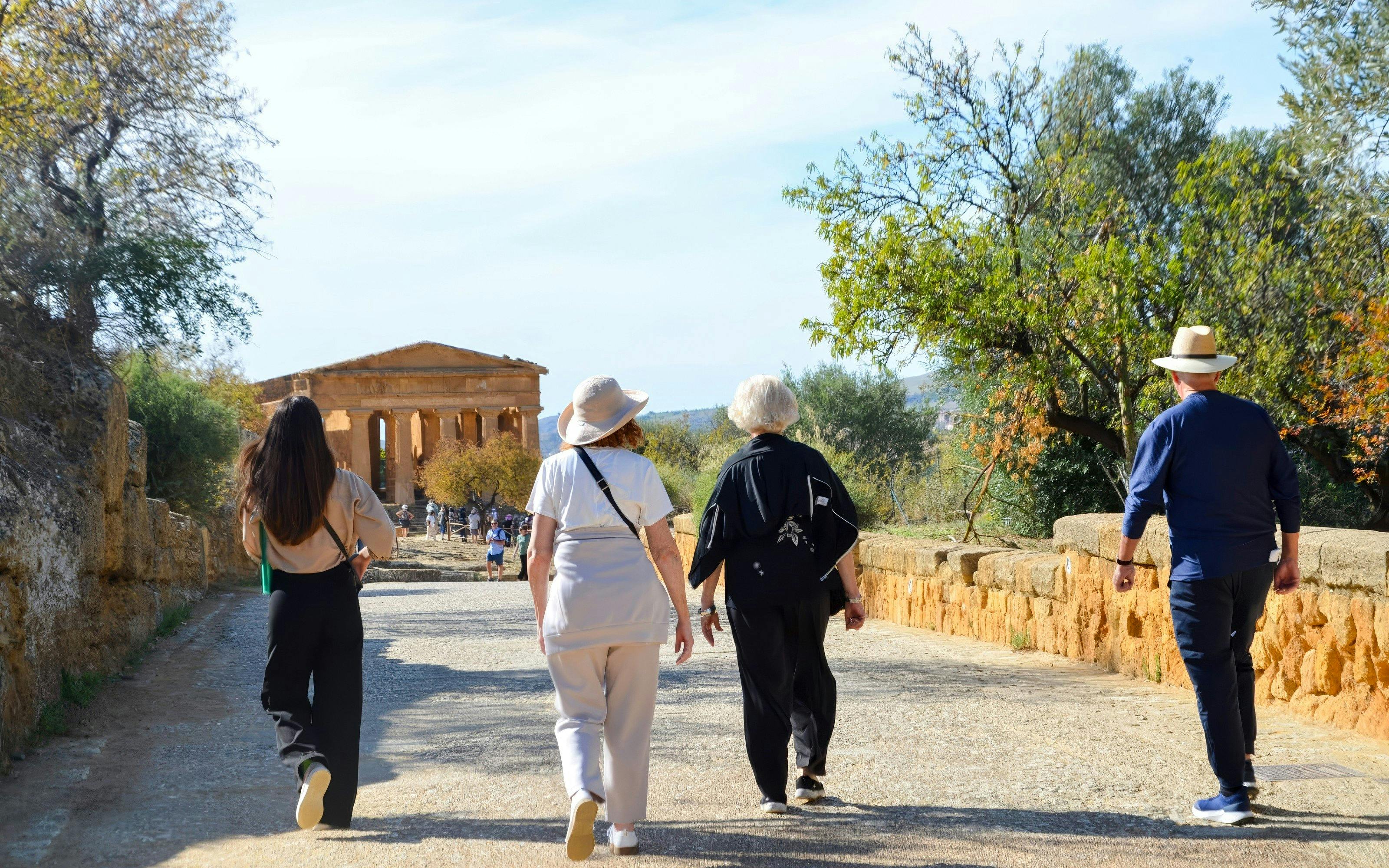 Visitors walking towards ancient temple ruins at Valley of Temples, Italy.
