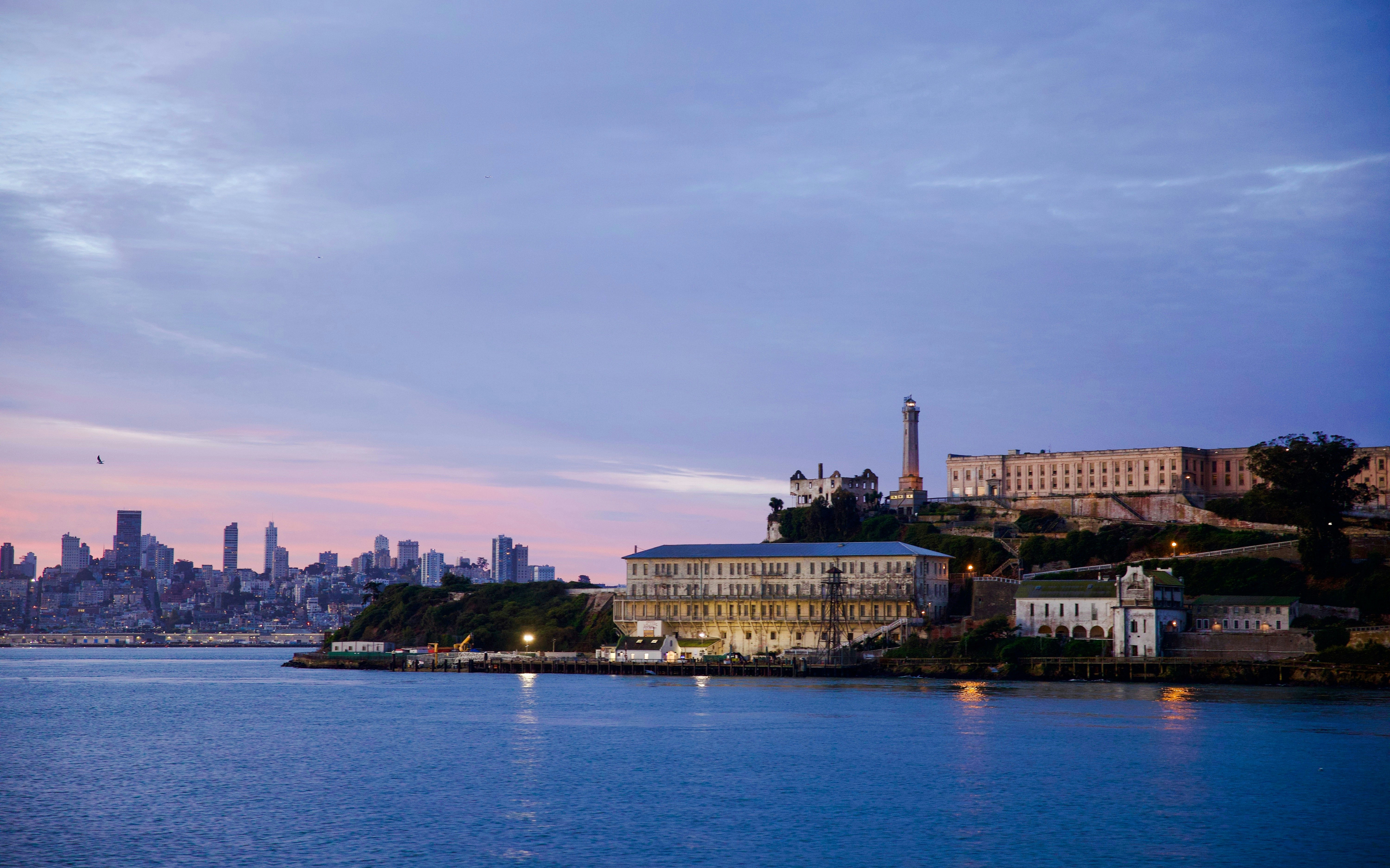 Alcatraz Island prison with San Francisco skyline at dusk.