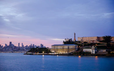 Alcatraz Island prison with San Francisco skyline at dusk.
