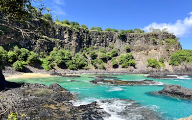 Cliffs and turquoise waters at Sancho Beach, part of the Noronha Boat Tour, Sao Paulo.