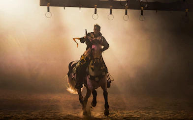 Knight on horseback aiming lance at rings during Medieval Times Orlando tournament.
