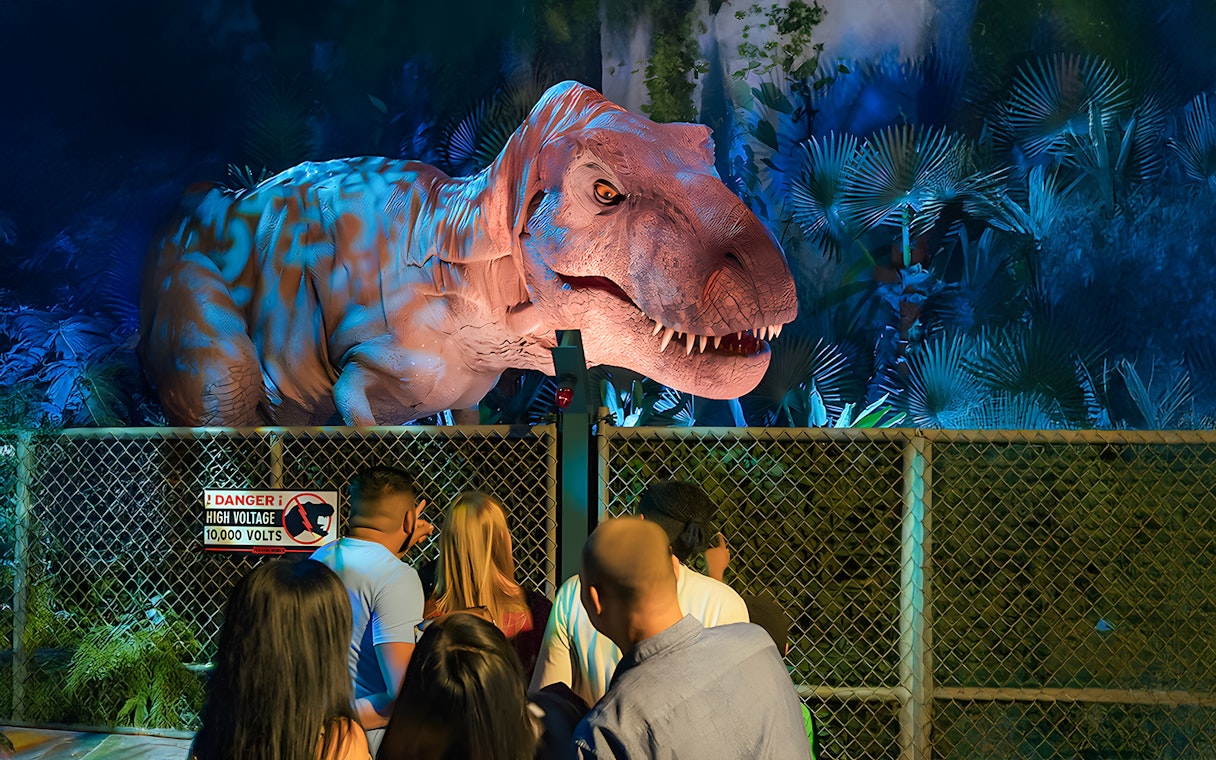 Visitors observing animatronic dinosaur at Jurassic World Experience, London.