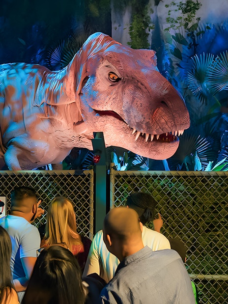 Visitors observing animatronic dinosaur at Jurassic World Experience, London.