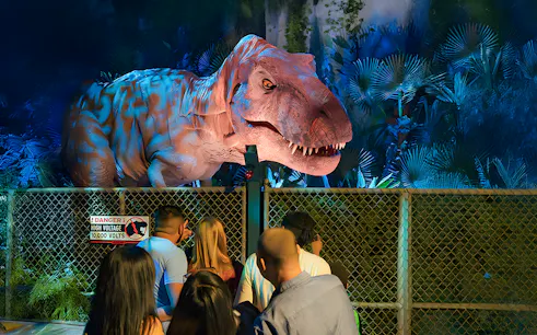 Visitors observing animatronic dinosaur at Jurassic World Experience, London.