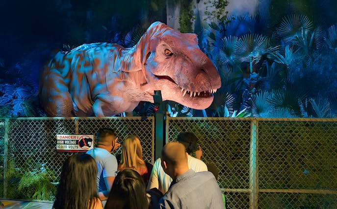 Visitors observing animatronic dinosaur at Jurassic World Experience, London.