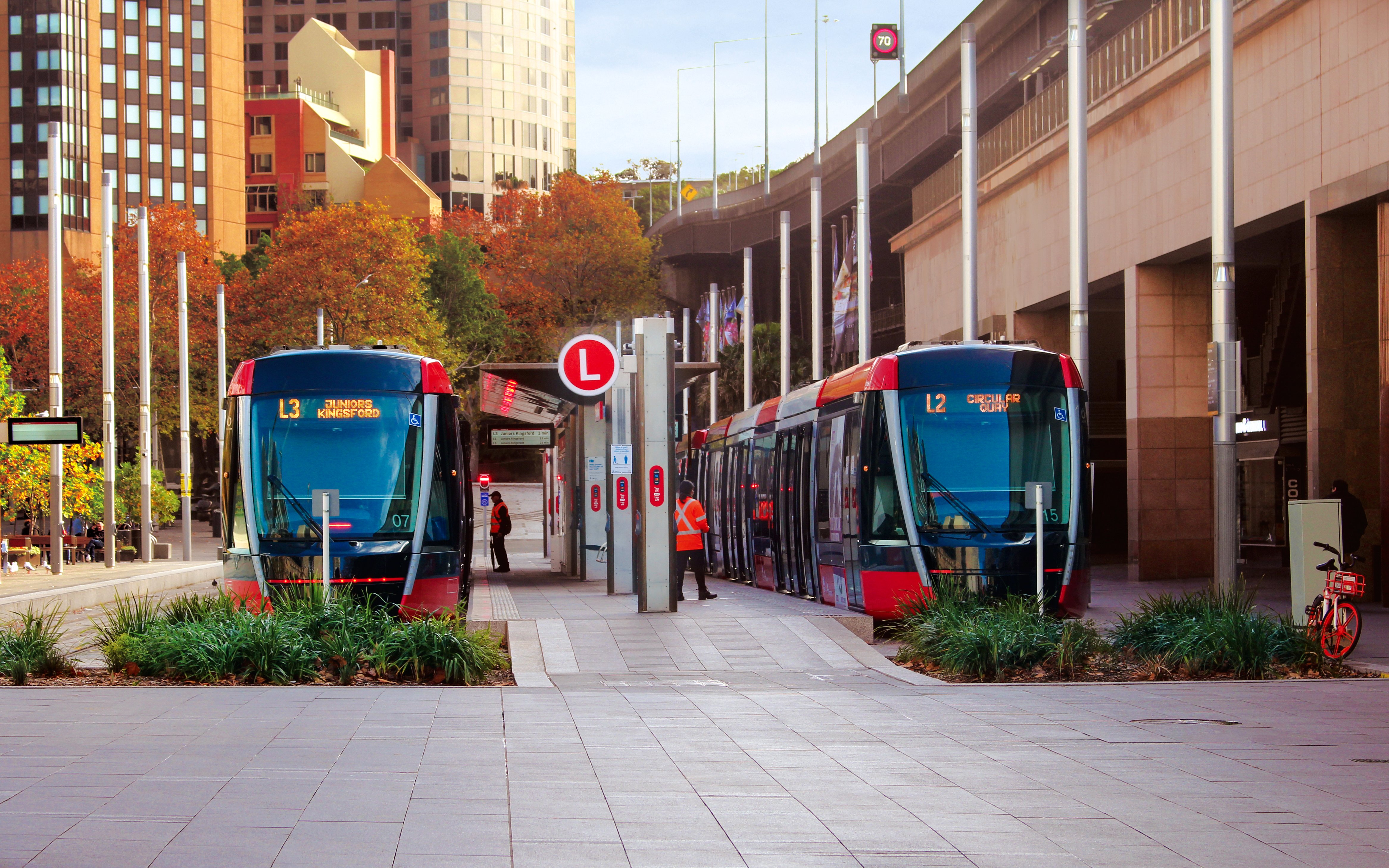 Streetscape outside Circular quay light rail station. Pictured are two light rail trains.