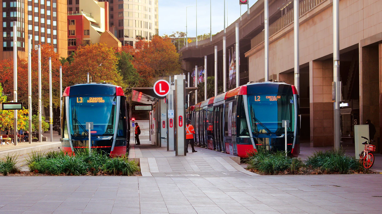 Two light rail trains at Circular Quay station in Sydney streetscape.