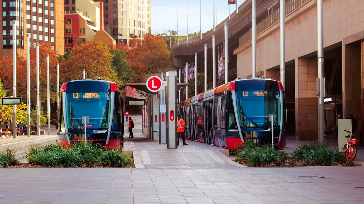 Streetscape outside Circular quay light rail station. Pictured are two light rail trains.