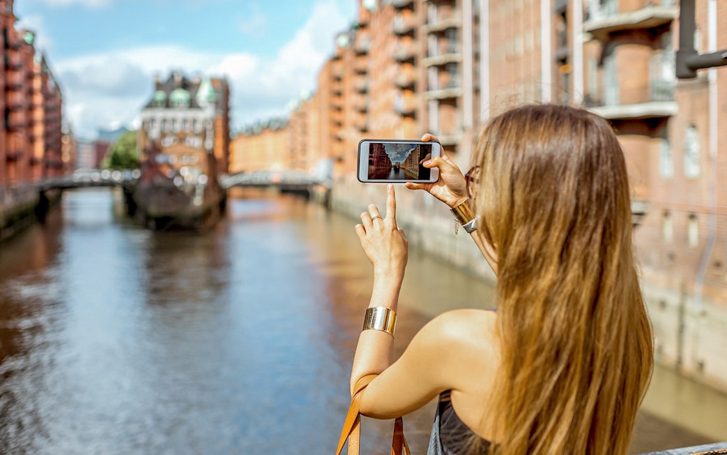 Woman photographing Speicherstadt canal in Hamburg, Germany.