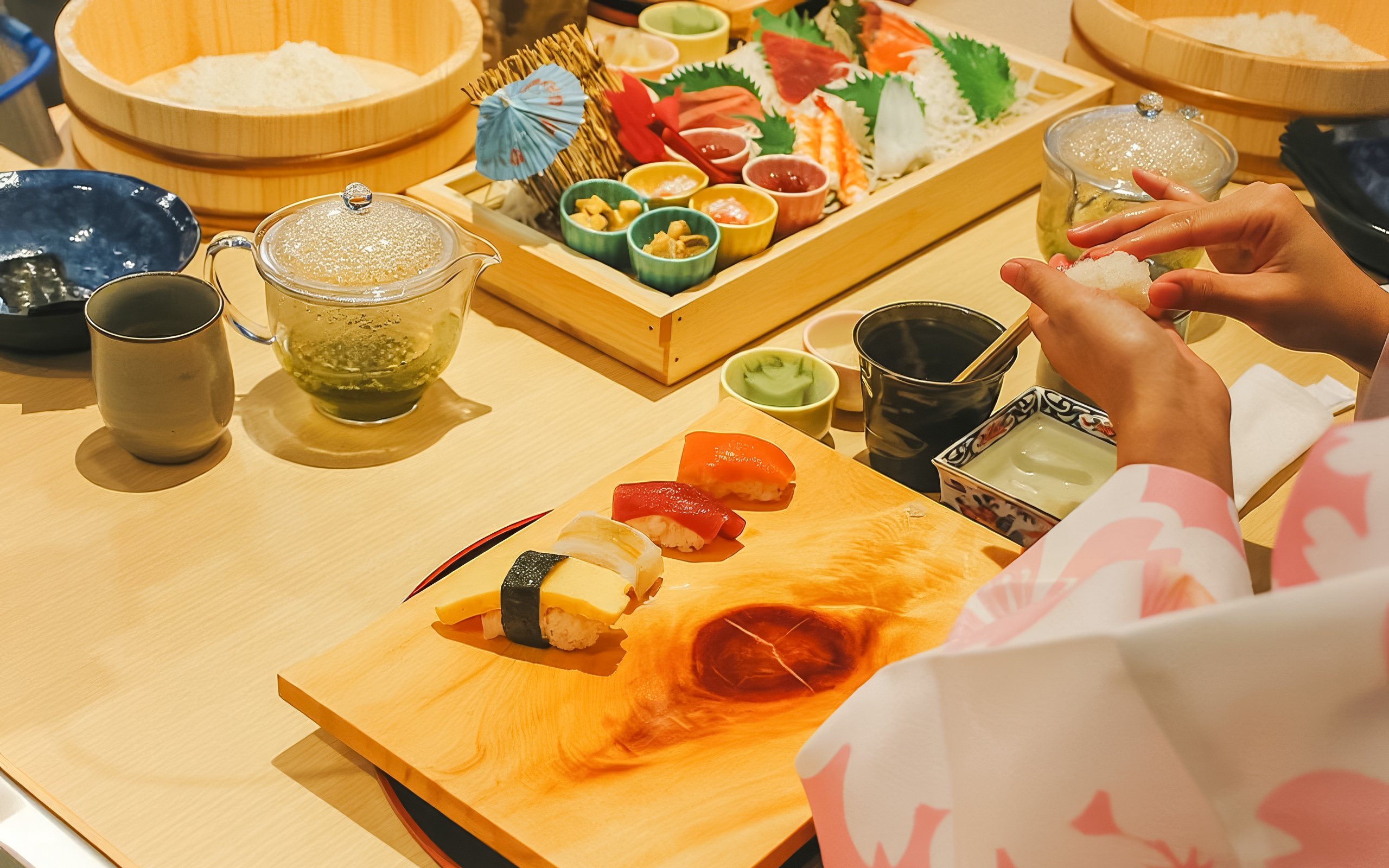 Tourist making sushi in traditional attire near Tokyo Tower with ingredients and tea set.