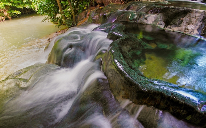 Water cascading over rocks into the Emerald Pool in Krabi, Thailand.