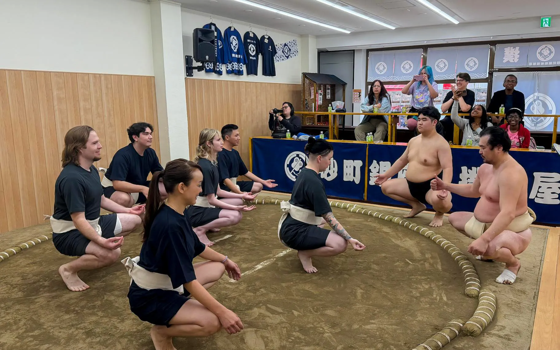 Participants in a sumo workshop learning traditional techniques in a Tokyo dojo.