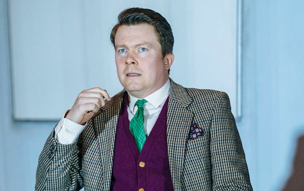 Man in a suit performing in "Accidental Death of an Anarchist" play.