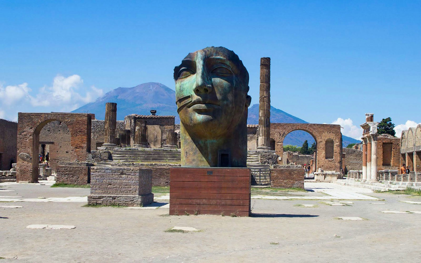 Ancient Pompeii ruins with large sculpture and Mount Vesuvius in background, Naples, Italy.
