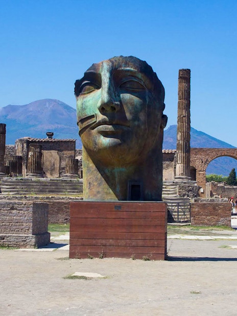 Ancient Pompeii ruins with large sculpture and Mount Vesuvius in background, Naples, Italy.