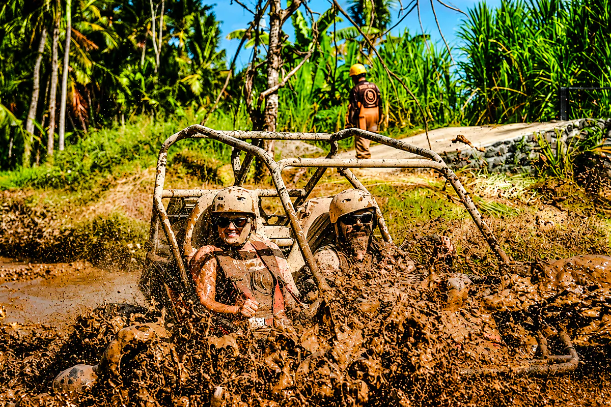 Buggy ride through muddy jungle track in Ubud, Bali with lush greenery in background.