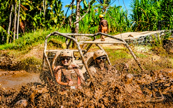 Buggy ride through muddy jungle track in Ubud, Bali with lush greenery in background.