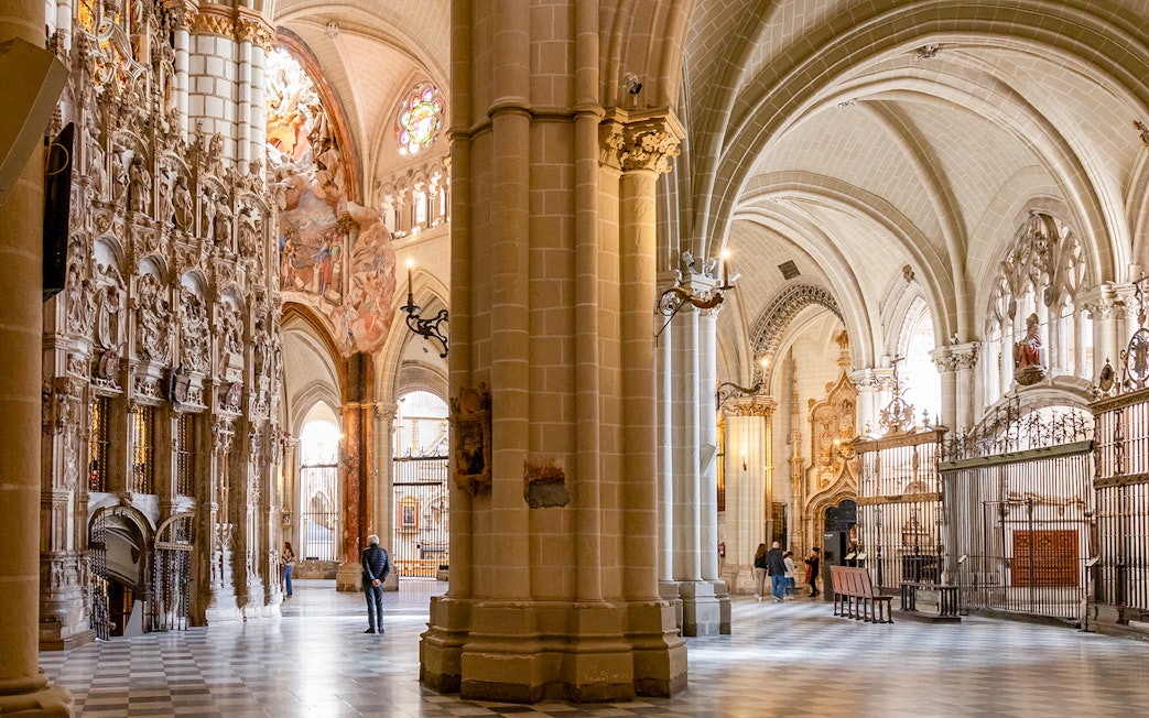 Toledo Cathedral interior with ornate stone carvings and vaulted ceilings.