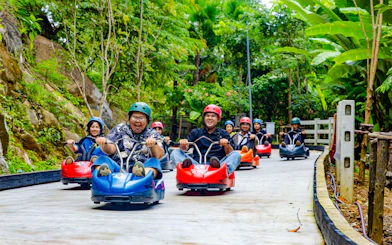 Friends enjoying the Hanuman Luge ride through a lush green forest.